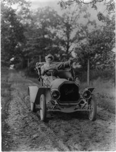 A woman sitting behind the wheel of a 1907 Buick.